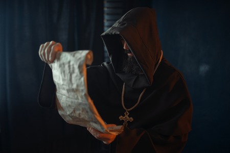 Medieval monk with an evil face reads a prayerの写真素材