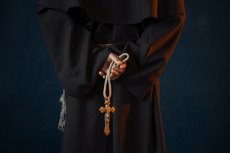 Monk holds wooden rosary and cross in handsの写真素材