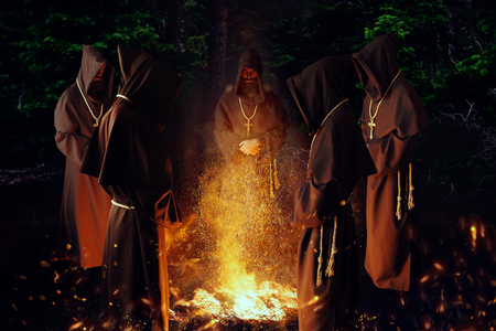 Medieval monks praying against a fire in the night