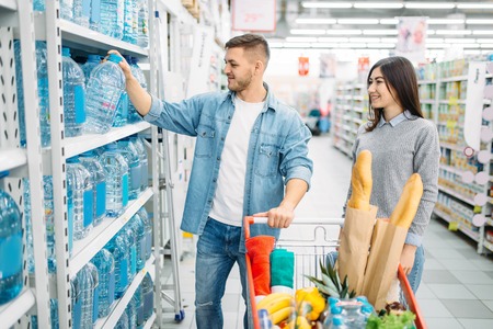 Couple takes canister of water in a supermarketの写真素材
