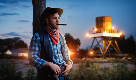 Brutal cowboy smokes a cigar on sunsetの写真素材