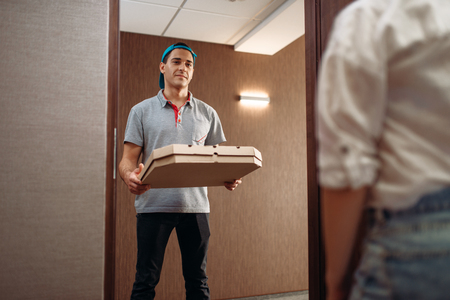 Pizza delivery boy with carton box on the doorstepの写真素材