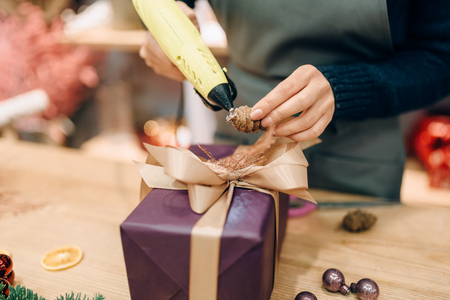 Female seller decorates gift box with fir coneの写真素材