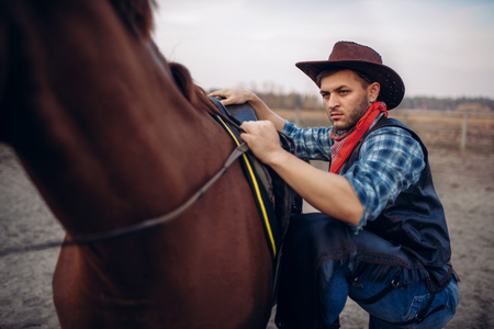 Brutal cowboy climbs on horseback on texas ranchの写真素材