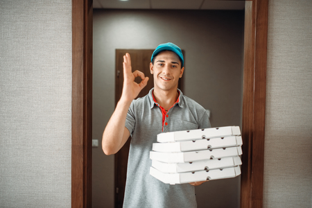 Cheerful pizza delivery boy shows Ok symbolの写真素材