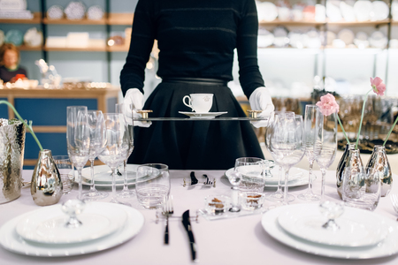 Waitress with tray puts the dishes, table settingの写真素材