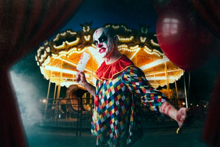 Scary bloody clown with baseball bat and balloon