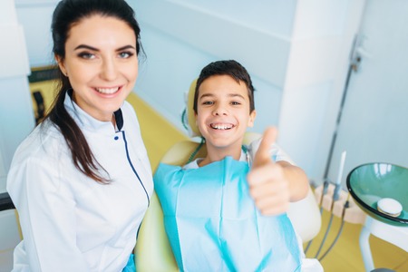 Little boy in a dental chair shows thumbs upの写真素材