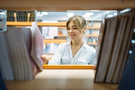 Female student choosing book in libraryの写真素材