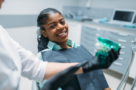 Dentist shows dentures to patient in dental clinicの写真素材