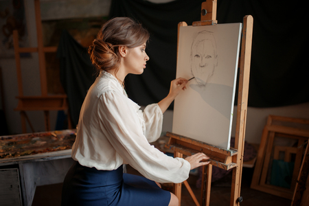 Female painter in studio, pencil sketch on easelの写真素材