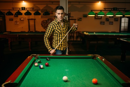 Male billiard player with cue at the table
