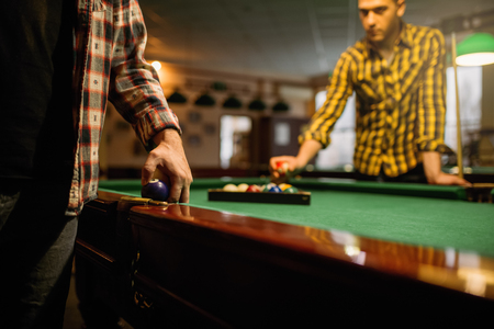Two male billiard players places colorful balls