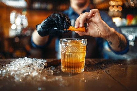 Bartender adds orange skins to alcoholic beverageの写真素材