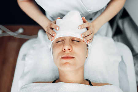 Beautician hands on female patient face, top viewの写真素材