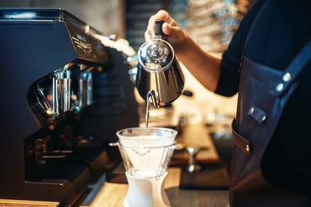 Barista pours hot water into the glass with coffeeの写真素材
