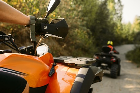 Two quad bike riders in helmets travels in forest, front view. Riding on atv, extreme sport and travelling, quadbike adventureの写真素材