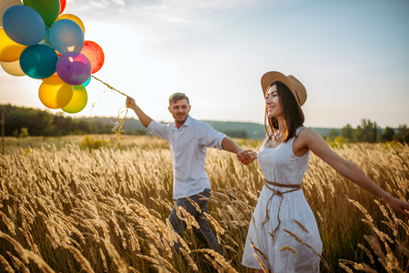 Love couple with balloons, leisure in a rye fieldの写真素材