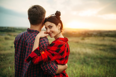 Happy love couple hugs in summer field at sunsetの写真素材