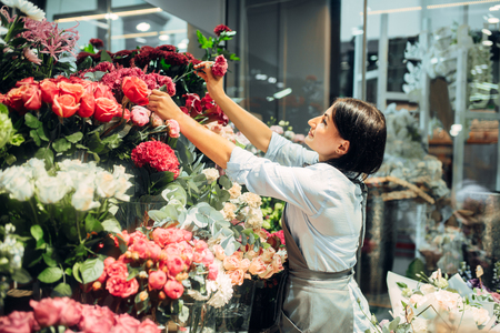Female florist selects flowers for making bouquetの写真素材