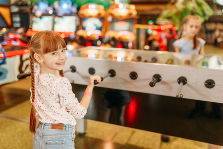 Happy girl at table soccer in children game centerの写真素材