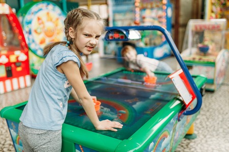 Two little girls plays air hockey in game center