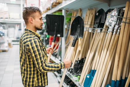Man buying shovel in supermarket, tools departmentの写真素材
