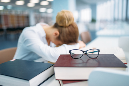 Female person sleeping at the table in libraryの写真素材