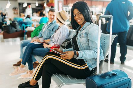 Female black tourist with suitcase in airportの写真素材