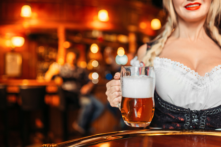 Large breasted waitress  holds mug of fresh beerの写真素材