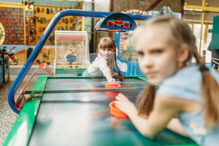 Two little girls plays air hockey in game centerの写真素材