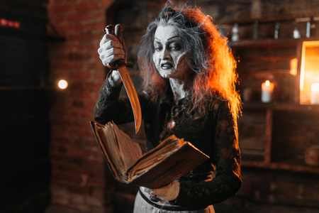 Scary witch holds spellbook and knifeの写真素材