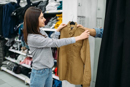 Couple choosing shirts in fitting room, storeの写真素材