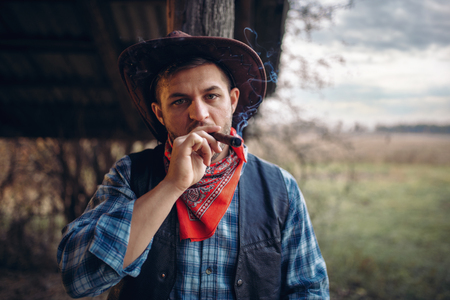 Brutal cowboy smokes a cigar, wild west culture