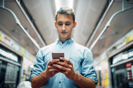 Man using phone in subway car, addicted peopleの写真素材