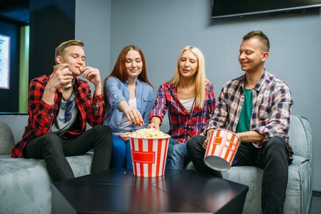 Friends eating popcorn and having fun in cinemaの写真素材