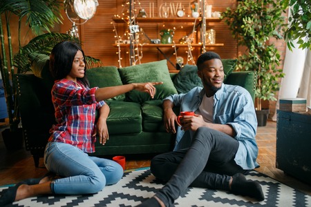 Black couple sitting on floor and drinks coffeeの写真素材