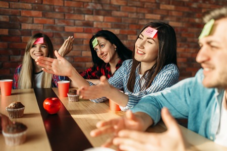 Smiling friends playing sticker notes to foreheadの写真素材