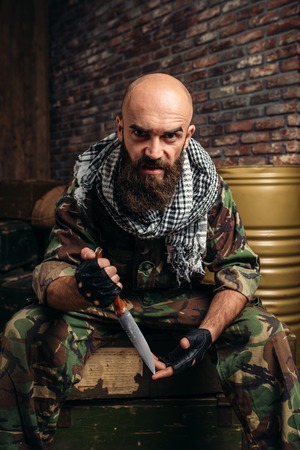 Terrorist with knife sits on boxes of ammunition