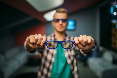 Male spectator shows 3d glasses in cinema hallの写真素材