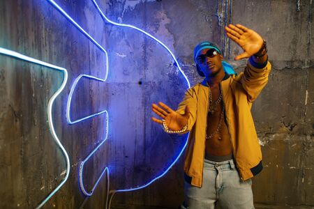 Black rapper in underpass neon light on background