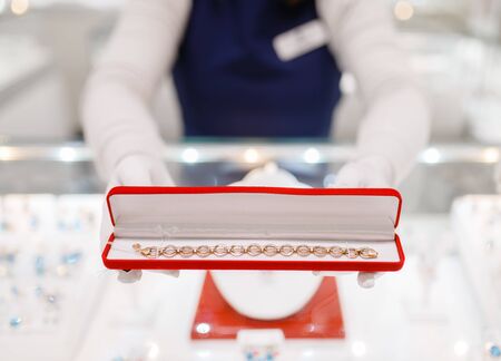 Female seller hands with gold bracelet in the caseの写真素材