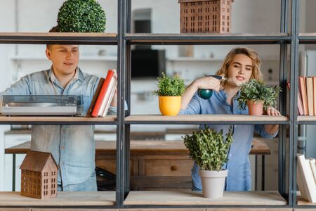 Young smiling couple at the shelf with home plantsの写真素材