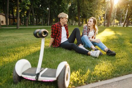 Young couple sitting on the grass near gyro boardの写真素材