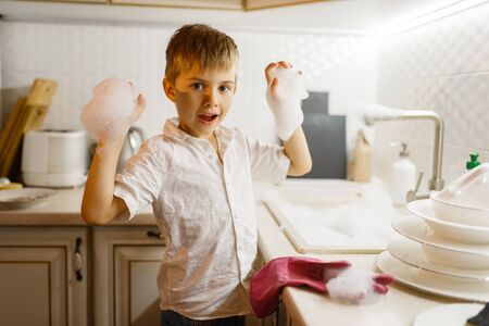 Little boy in gloves washing dishes on the kitchenの写真素材