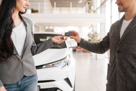 Couple buying new car, man gives the key to womanの写真素材