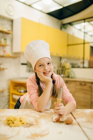 Little girl cook in cap and apron on the kitchenの写真素材