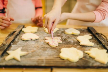 Two little girls cooks spread out cookies on boardの写真素材
