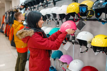Couple choosing helmets, shopping in sports shopの写真素材