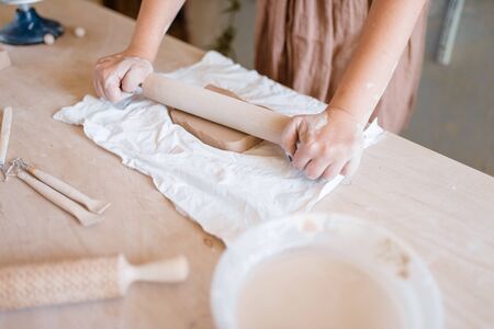 Female potter roll out foarm with a rolling pin